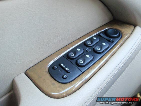 Car door panel with wood trim and window controls, including memory seat buttons