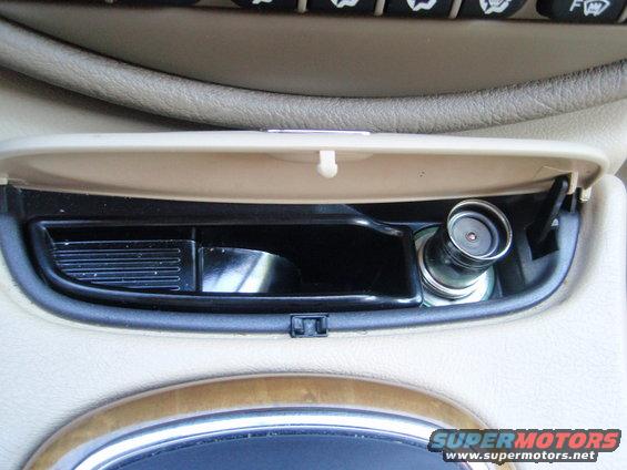 Car interior with open ashtray compartment showing a cigarette lighter and a ribbed slot