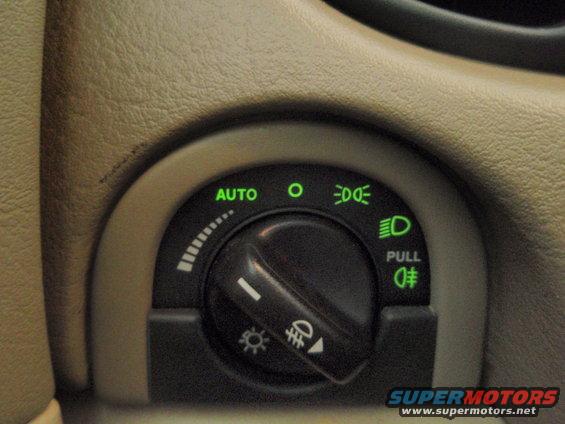 Close-up of a car's headlight control dial with 'AUTO' illuminated