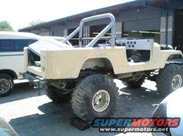 Yellow off-road vehicle body with roll cage, large tires, and exposed engine bay