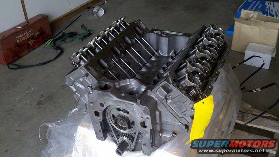 Engine block with valve covers and timing chain visible, yellow tag attached
