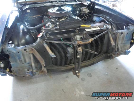 Car's engine bay with the front grille and bumper removed, showing the radiator and engine components
