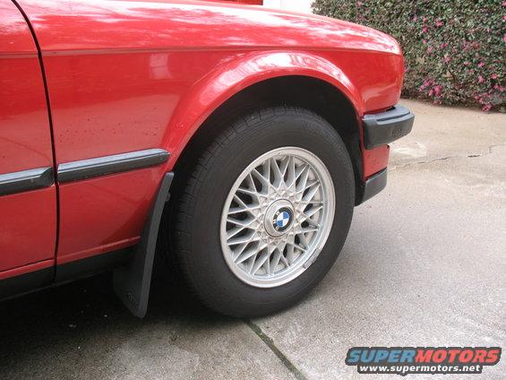 Red 1986 BMW 3 Series front fender and wheel, showing a multi-spoke alloy wheel with a BMW logo