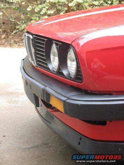 Front view of a red BMW 3 Series with dual headlights and black bumper
