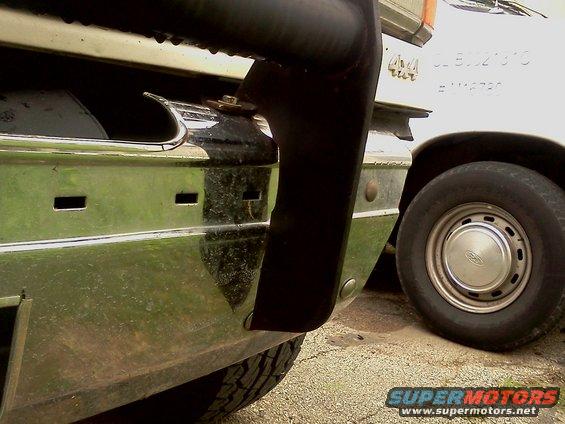 1989 Ford Bronco front bumper with chrome trim and black grille guard. White vehicle with 4x4 badge visible behind