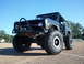 1967 Ford Mustang - Modified Ford Bronco with large off-road tires and a custom bumper sits on a gravel lot under a clear blue sky.