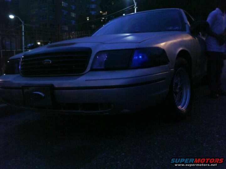 Front view of a silver Ford Crown Victoria with aftermarket headlights and wheels