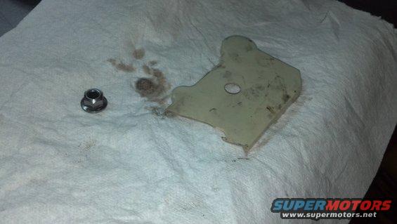 Metal bracket and a nut on paper towels with oil stains