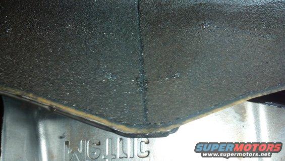 Close-up of a textured black surface with a metal component underneath that has the word "WELLIC" stamped on it