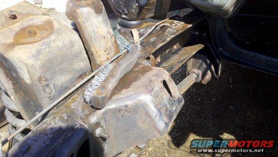 Rusty vehicle suspension parts with a wire brush being used