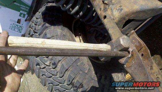 Suspension part being worked on with a hammer and bar