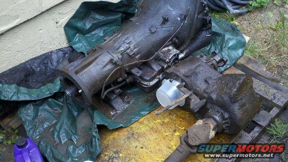 Transmission and transfer case assembly, oily, on tarp and wood