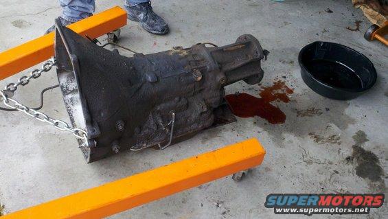 Transmission on engine hoist with oil pan and spilled fluid