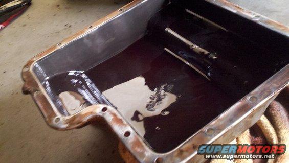 Transmission pan filled with dark fluid, showing some sludge and a dipstick