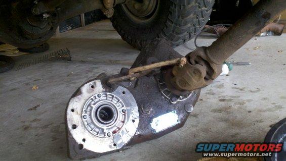 Transfer case with driveshaft attached, viewed from side. Part is dirty and appears used