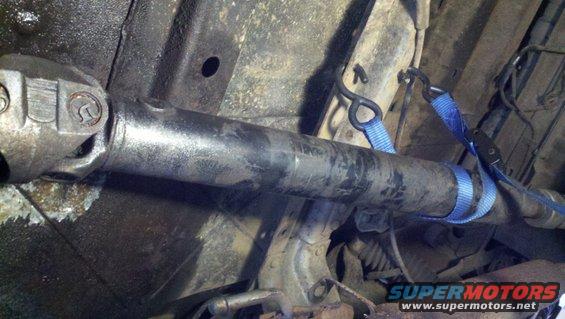 Underside view of a vehicle driveshaft secured with blue straps
