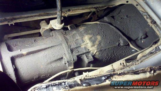 Transmission housing covered in grime, viewed from underneath a vehicle