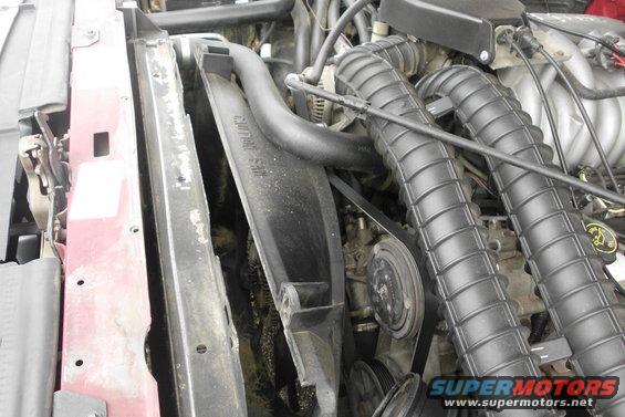 Engine bay showing fan shroud, air intake hoses, and belts