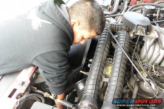 guy working on car engine, looking at air intake