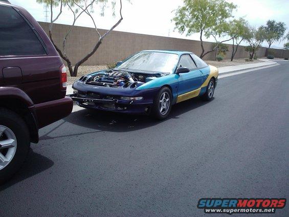 1993 Ford Probe with hood open, parked next to a maroon SUV