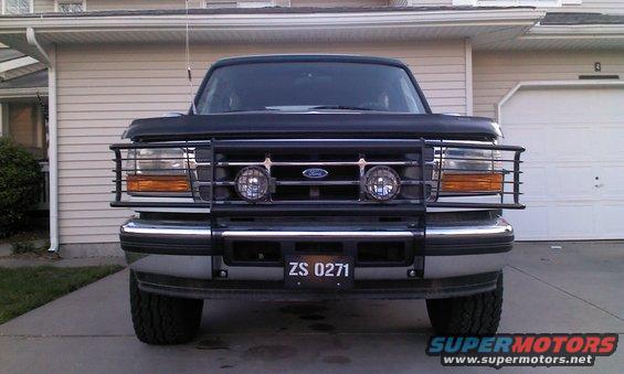Black Ford truck with a brush guard and two round lights, front view