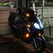 2008 Yamaha Zuma - A dark blue scooter is shown from the front with its lights on.
