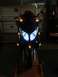 2008 Yamaha Zuma - A dark motorcycle is viewed from the front, its headlights and turn signals illuminated.