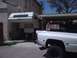 1997 Dodge 3500 - A white Dodge Ram pickup truck is parked next to a house, with a camper mounted in its bed.