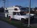 1997 Dodge 3500 - A white pickup truck is equipped with a camper shell, parked curbside with a traffic cone in front of the rear wheel.