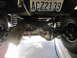 1974 Ford Bronco - The underside of a vehicle is visible, including its suspension components and a license plate.