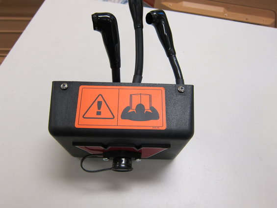 Black control box with three black levers, an orange warning sticker, and a red emblem