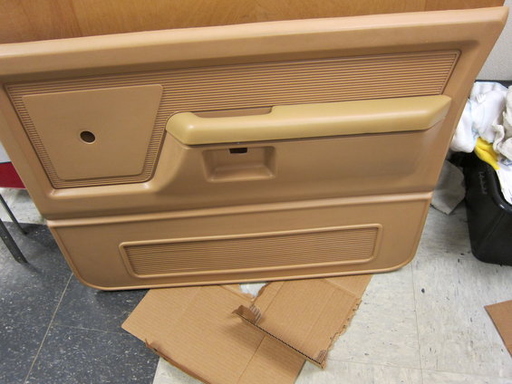 Tan truck door panel showing armrest, speaker grille, and window crank hole