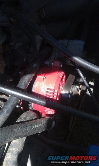 Close-up of a red alternator with a belt and hoses