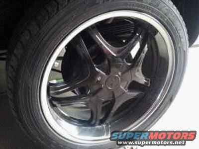 Close-up of a black five-spoke aftermarket wheel with a chrome lip