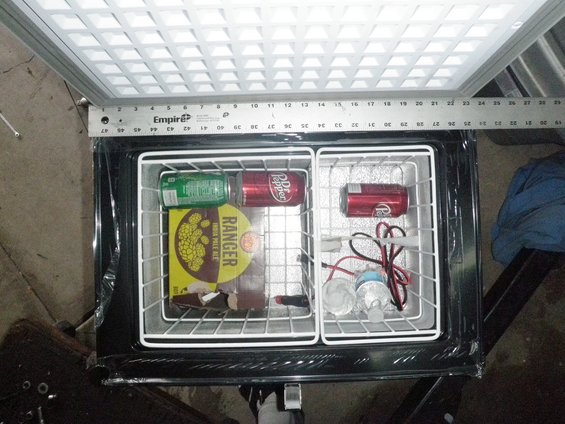 Portable refrigerator interior with Dr Pepper and Coca-Cola cans, a box of Ranger brand items, and water bottles