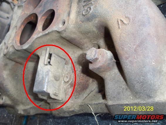 Cast iron engine part with a red circle around a metal bracket