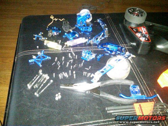 Blue remote control car parts and tools scattered on a black surface