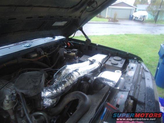 Engine bay with aluminum-wrapped intake tubes, green exterior paint, and a Supermotors.net watermark
