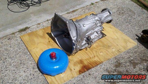 Silver automatic transmission and blue torque converter on plywood