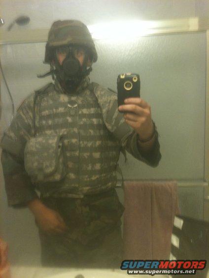 Person in helmet, gas mask, and camouflage uniform takes a mirror selfie