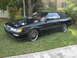 1992 Infiniti M30 - A black convertible with a black soft top is parked on a grassy area next to a sidewalk.