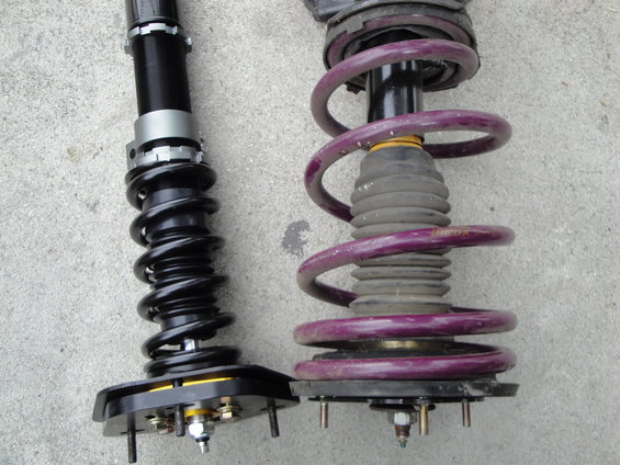Comparison of two car suspension coilover assemblies, one black and one with purple springs