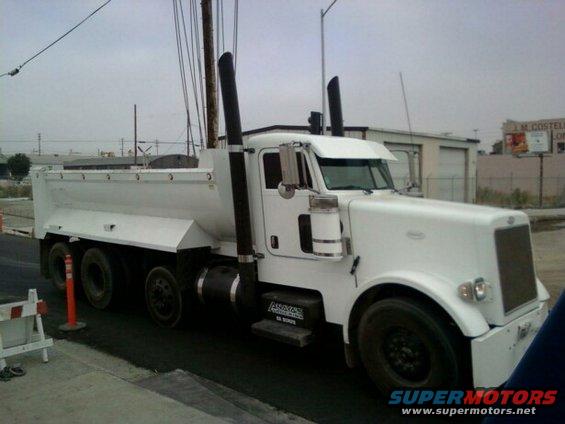 White dump truck with large exhaust stacks parked on a street