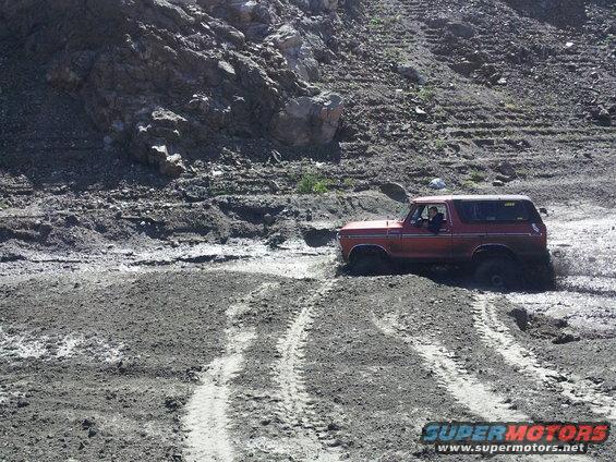 red 1978 Ford Bronco driving through mud