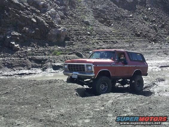 1978 Ford Bronco with lifted suspension driving through mud and water