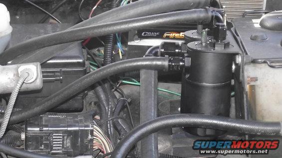 Black oil catch can with braided hoses in engine bay. Crane FireS logo visible