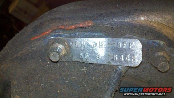 Metal identification tag with numbers and letters on a rusty component