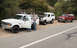 1994 Ford Bronco - Three Ford Broncos are parked on the shoulder of a road, with one white Bronco's hood open and a person standing by the driver's door.