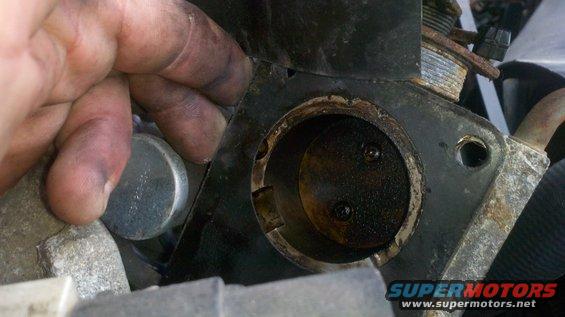 Close-up of a dirty engine part with a hand visible