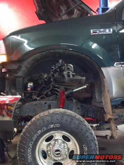 Green truck front view, hood open, engine exposed. F250 badge visible